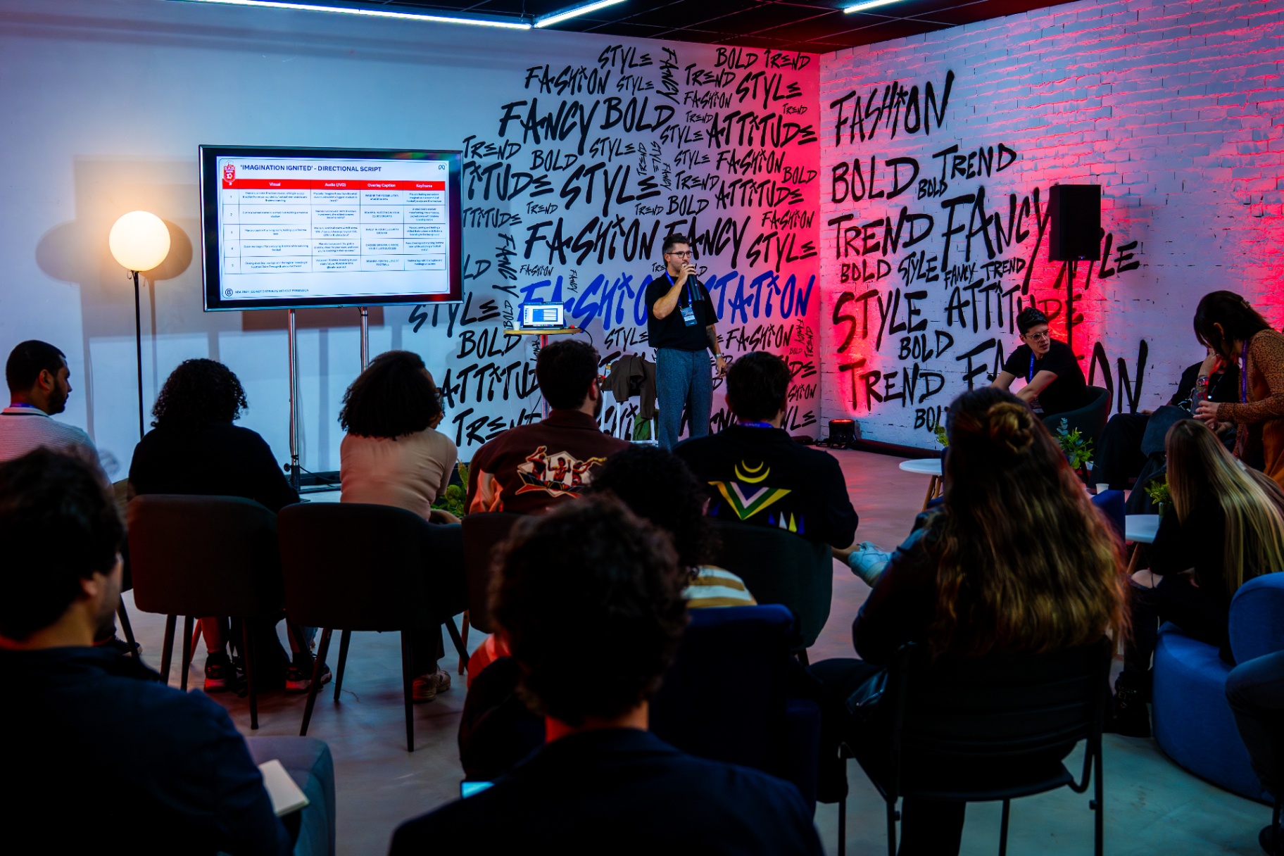 Sala de palestra com parede grafitada e apresentação para criadores.