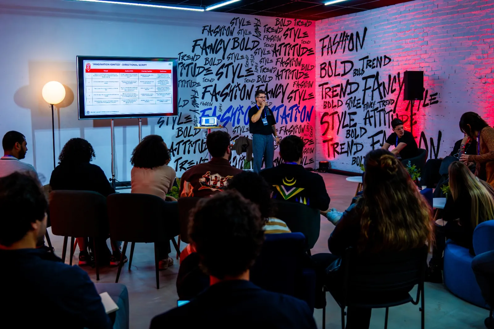 Sala de palestra com parede grafitada e apresentação para criadores.